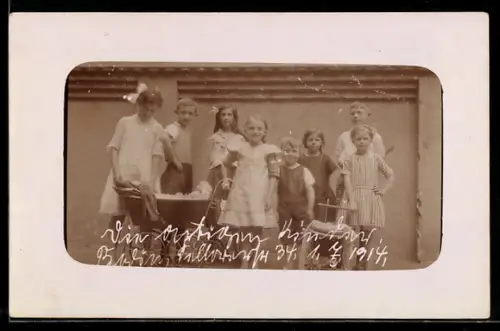 Foto-AK Kindergruppe mit zwei Puppenwagen vor einer Wand im Freien, 1914