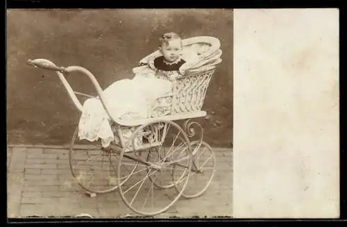 Foto-AK Kleinkind im Kinderwagen vor einer Wand im Freien