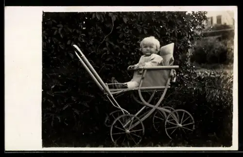 Foto-AK Weissblondes Kleinkind im Kinderwagen neben einer Hecke