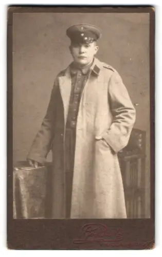 Fotografie Joh. Bartz, Kiel, Adelheidstrasse, Soldat im Uniformmantel mit Schirmmütze