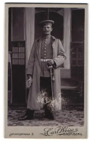 Fotografie Carl Weiss, Bromberg, Johannisstrasse 8, Soldat in Uniform mit Mantel, Krätzchen und Säbel