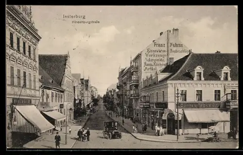 AK Insterburg, Hindenburgstrasse mit Geschäft Conrad Tack und anderen Geschäften, Passanten und Auto vorne