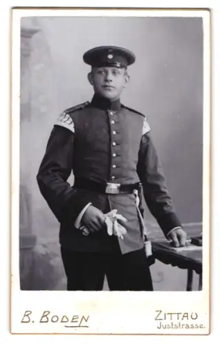 Fotografie B. Boden, Zittau, Juststrasse 2, Spielmann in Uniform mit Schirmmütze und Bajonett