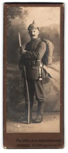 Fotografie Fr. Wäger, Altona, Holstenstr. 117, Soldat in Feldgrau Uniform mit Pickelhaube, Gewehr, Tornister u. Bajonett