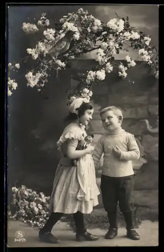 Foto-AK L.J. & F.F. Nr. 3497/5: Kleines Paar unter blühendem Zweig, Puppe
