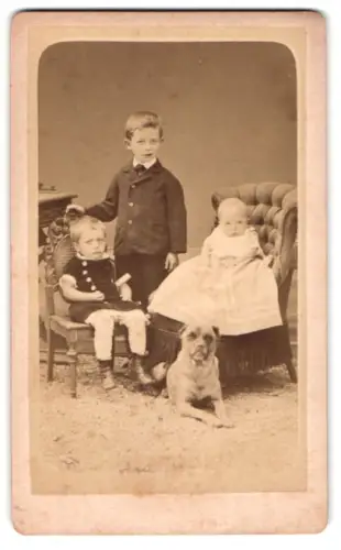 Fotografie unbekannter Fotograf und Ort, drei niedliche Kinder mit ihrem Hund zu Füssen
