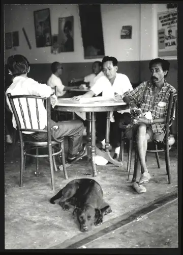 Fotografie Hermann Engel, Köln-Klettenberg, Weisshausstr. 36, Malaysien, Männer sitzen an einem Tisch, Hund liegt daneben
