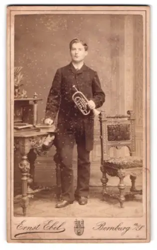 Fotografie Ernst Ebel, Bernburg A/S., Wilhelm-Strasse Ecke Kaiserstr., Bursche mit Trompete im Foto-Atelier
