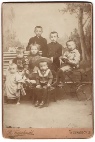 Fotografie B. Freischmidt, Zyrardow, Knabe auf Dreirad nebst Geschwistern in Sonntagsbekleidung