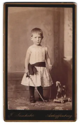 Fotografie Atelier Samhaber, Aschaffenburg, Knabe mit Reitgerte & Spielzeug-Pferd