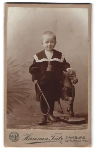 Fotografie Hermann Tietz, Hamburg, Gr. Burstah 12-14, Blonder Knabe mit Reitgerte & Spielzeug-Pferd
