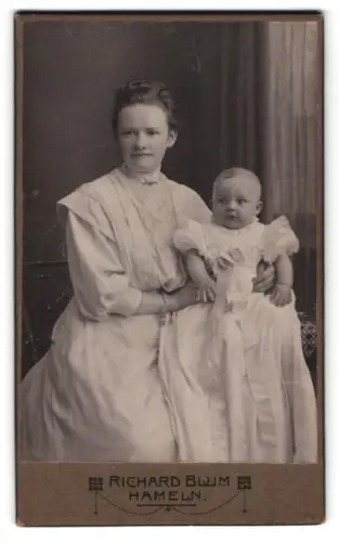 Fotografie Richard Blum, Hameln, glückliche Mutter hält Baby im Taufkleid