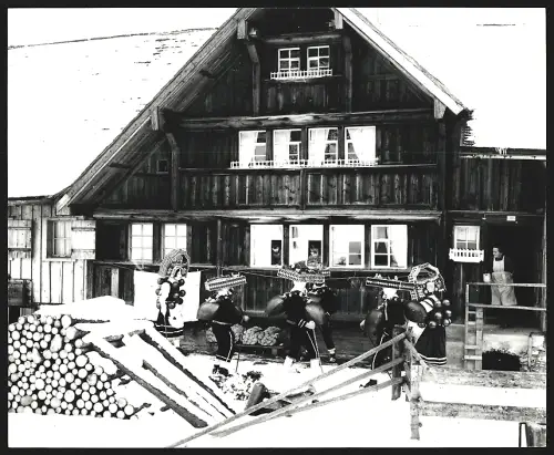 Fotografie Ansicht Urnäsch, Silvesterklausen, Gruppe in traditionellen Kostümen vor einem Haus, Kinder in den Fenstern