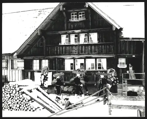 Fotografie Ansicht Urnäsch, Silvesterklausen, Gruppe in traditionellen Kostümen vor einem Haus im Schnee