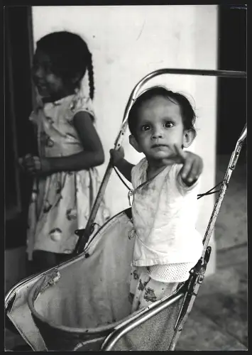 Fotografie Hermann Engel, Köln-Klettenberg, Weinhausstr. 36, Malaysia, Kleinkind steht in einem Kinderwagen, 25 x 18cm
