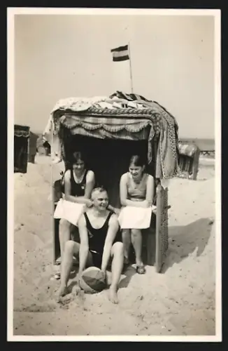 Fotografie Mann und zwei Frauen mit Ball an einem Strandkorb