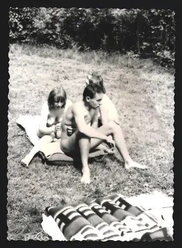 Fotografie Mann und zwei nackte Frauen sitzen auf einer Decke