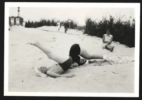 Fotografie Zwei Frauen in Badeanzügen turnen im Sand