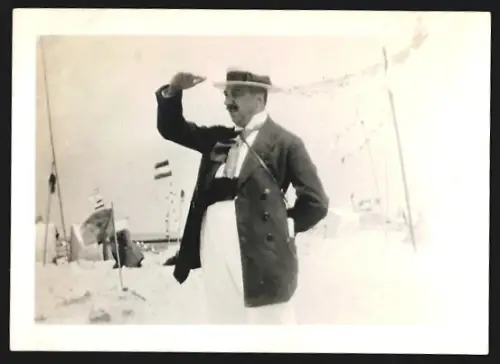 Fotografie Eleganter Mann mit Hut schirmt sein Gesicht vor der Strandsonne ab