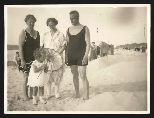 Fotografie Familie in Badeanzügen geniesst einen sonnigen Tag am Strand