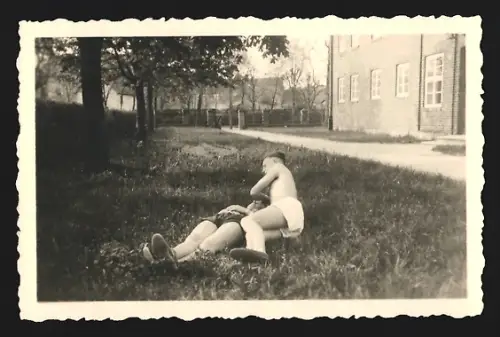 Fotografie Zwei Personen in Badehosen liegen auf einer Wiese und ruhen sich aus