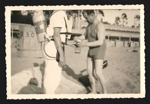 Fotografie Mann im Badeanzug kauft ein Getränk bei einem mobilen Limonaden-Verkäufer am Strand