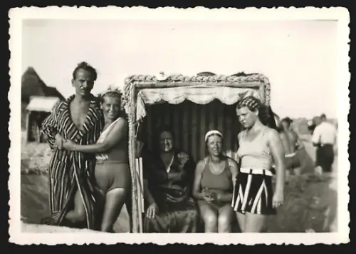 Fotografie Menschengruppe in Badekleidung geniesst die Dämmerung an einem Strandkorb