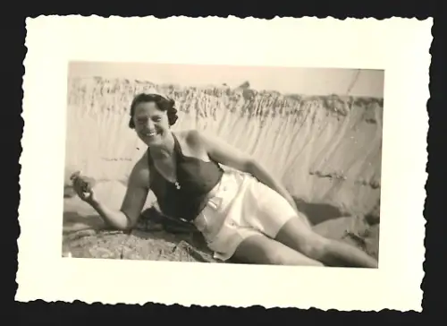 Fotografie Lächelnde Frau in Badebekleidung liegt im Sand