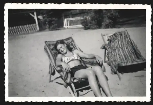 Fotografie Junge Frau im Bikini sonnt sich auf einem Liegestuhl