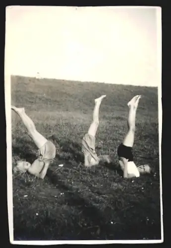 Fotografie Drei Personen machen Turnübungen auf einer Wiese