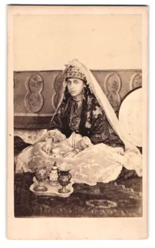 Fotografie junge Araberin in Tracht / Gewand mit Kopftuch beim Tee trinken