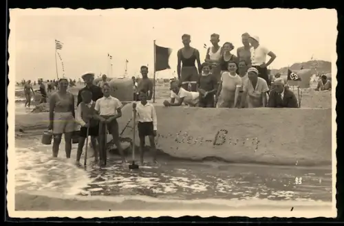 Foto-AK Junge Menschen auf einer Sandburg am Strand, Sandplastik, flagge