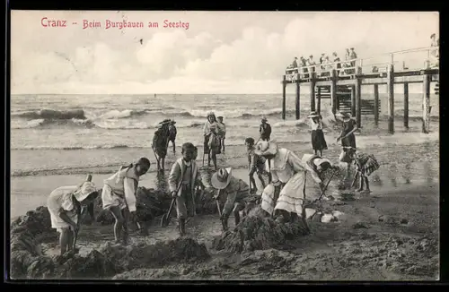 AK Cranz, Menschen beim Bauen einer Sandburg am Seesteg, Sandplastik