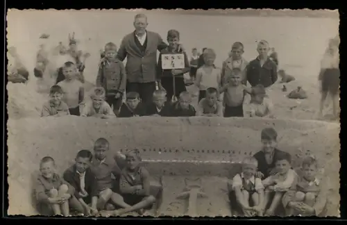 Foto-AK Mann mit vielen Kindern am Strand in einer Sandplastik