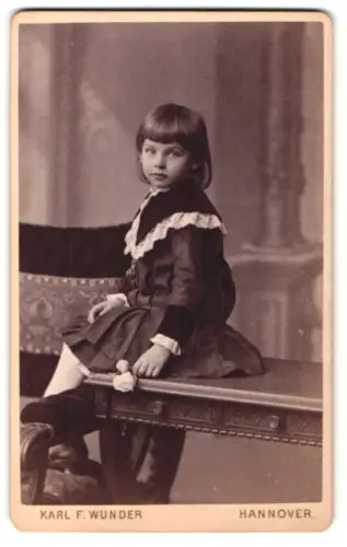Fotografie Karl F. Wunder, Hannover, Friedrichstrasse, Kind in elegantem Kleid auf einem Tisch sitzend