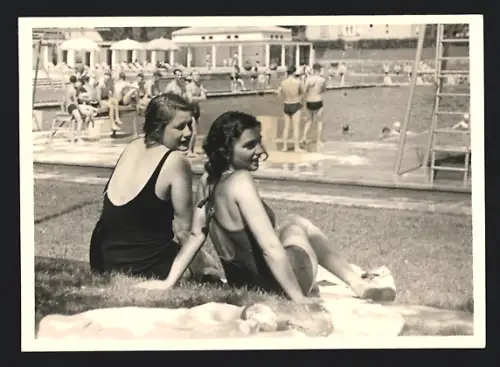 Fotografie Bademode, junge Frauen im Badeanzug auf Liegewiese vor Schwimmbecken sitzend