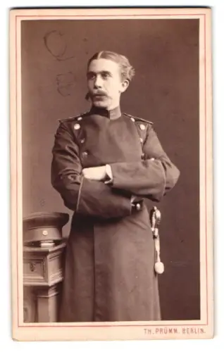 Fotografie Th. Prümm, Berlin, Unter den Linden 51, Offizier im Überrock mit Schirmmütze und Säbel