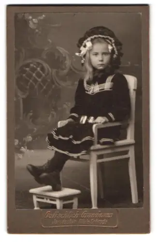 Fotografie Gottschlich-Grundmann, Jarotschin, Mädchen in elegantem Kleid und Haube auf Stuhl sitzend