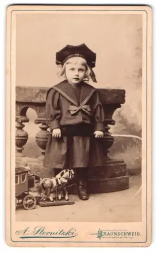 Fotografie A. Sternitzki, Braunschweig, Steinweg 10, Kind in Matrosenkleid mit Spielzeugpostkutsche