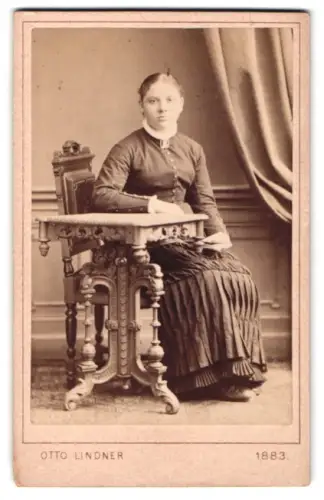 Fotografie Otto Lindner, Berlin, Königstrasse 31, Frau in elegantem Kleid an dekorativem Tisch