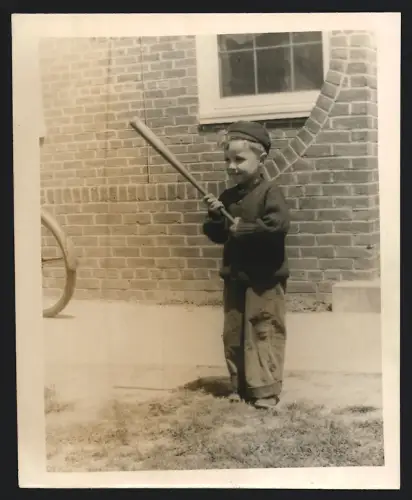 Fotografie Knabe mit Holzschläger spielt auf einem Hinterhof