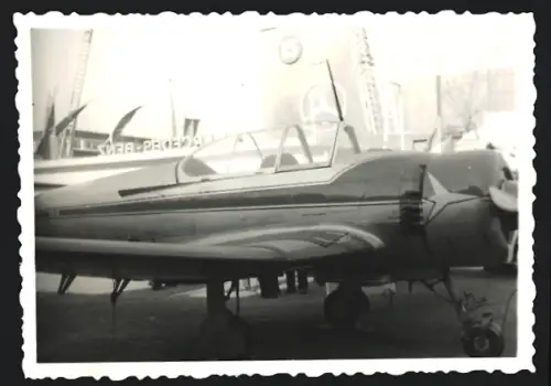 Fotografie Flugzeug Niederdecker, Zweisitzer Kunstflugmaschine vor Messe-Pavillon No. 15 von Mercedes Benz