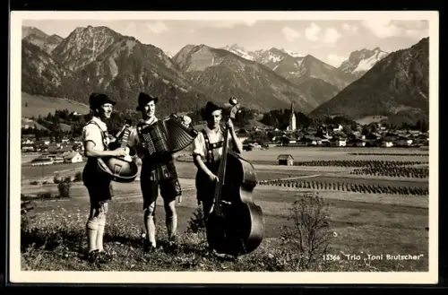 AK Trio Toni Brutscher, mit Instrumenten in Trachten vor der Stadt Oberstdorf, Blick zur Kirche
