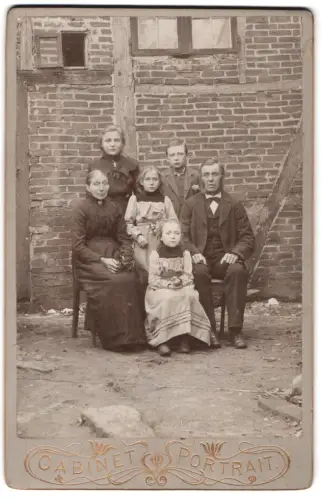 Fotografie unbekannter Fotograf und Ort, Familienporträt vor Backsteingebäude