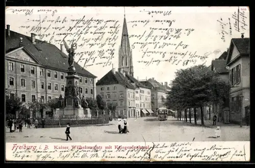 AK Freiburg i. B., Kaiser-Wilhelmsplatz mit Kriegerdenkmal, Kirchturm, Strassenbahn