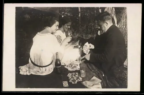 Foto-AK Zwei Frauen und ein Mann beim Kartenspiel im Wald