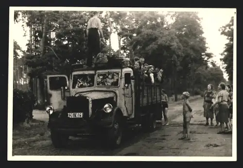 7 Fotografien Lastwagen mit Holzvergaser, LKW-Pritsche transportiert Einheimische zu einem Volksfest