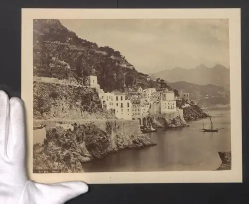Fotografie unbekannter Fotograf, Ansicht Atrani, Gebäude in der Felswand der Küste, Segelboote am Ufer, 24 x 30cm
