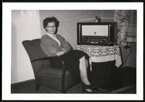Fotografie Hausfrau im Sessel neben Radio / Radioempfänger sitzend