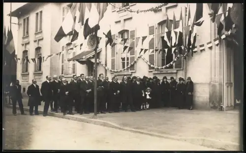 Fotografie unbekannter Fotograf, Ansicht Thaon, Jubiläumsfeier 1925, Einheimische & Flaggenschmuck